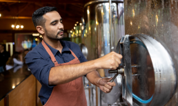 Employee at a brewery adjusting a tank