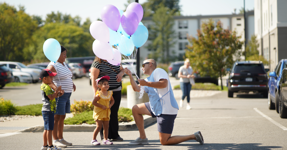 Pioneer employee handing balloon to child during the Grand Carnival 