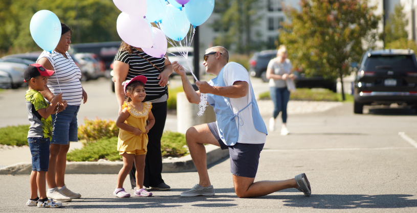 Pioneer employee handing balloon to child during the Grand Carnival 