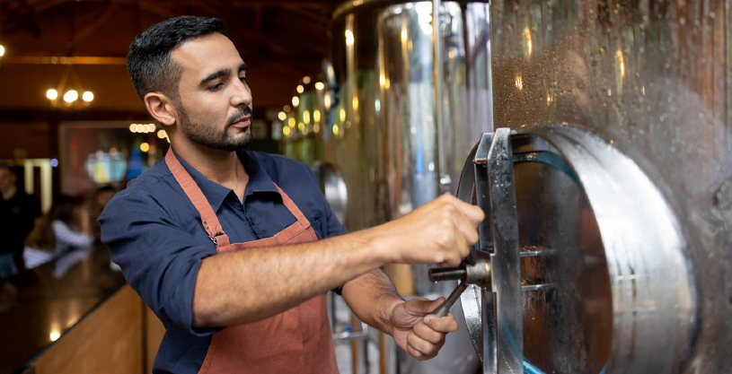 Employee at a brewery adjusting a tank